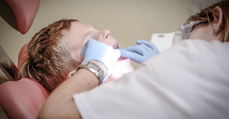 Dental - Dentist Woman Wearing White Gloves and White Scrubsuit Checking Boy's Teeth