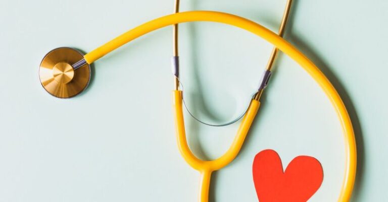 Clinics - Medical stethoscope with red paper heart on white surface