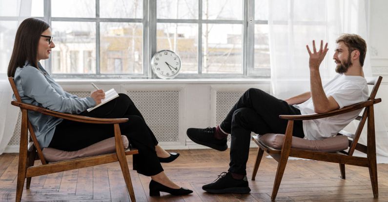 Therapist - Person in Black Pants and Black Shoes Sitting on Brown Wooden Chair